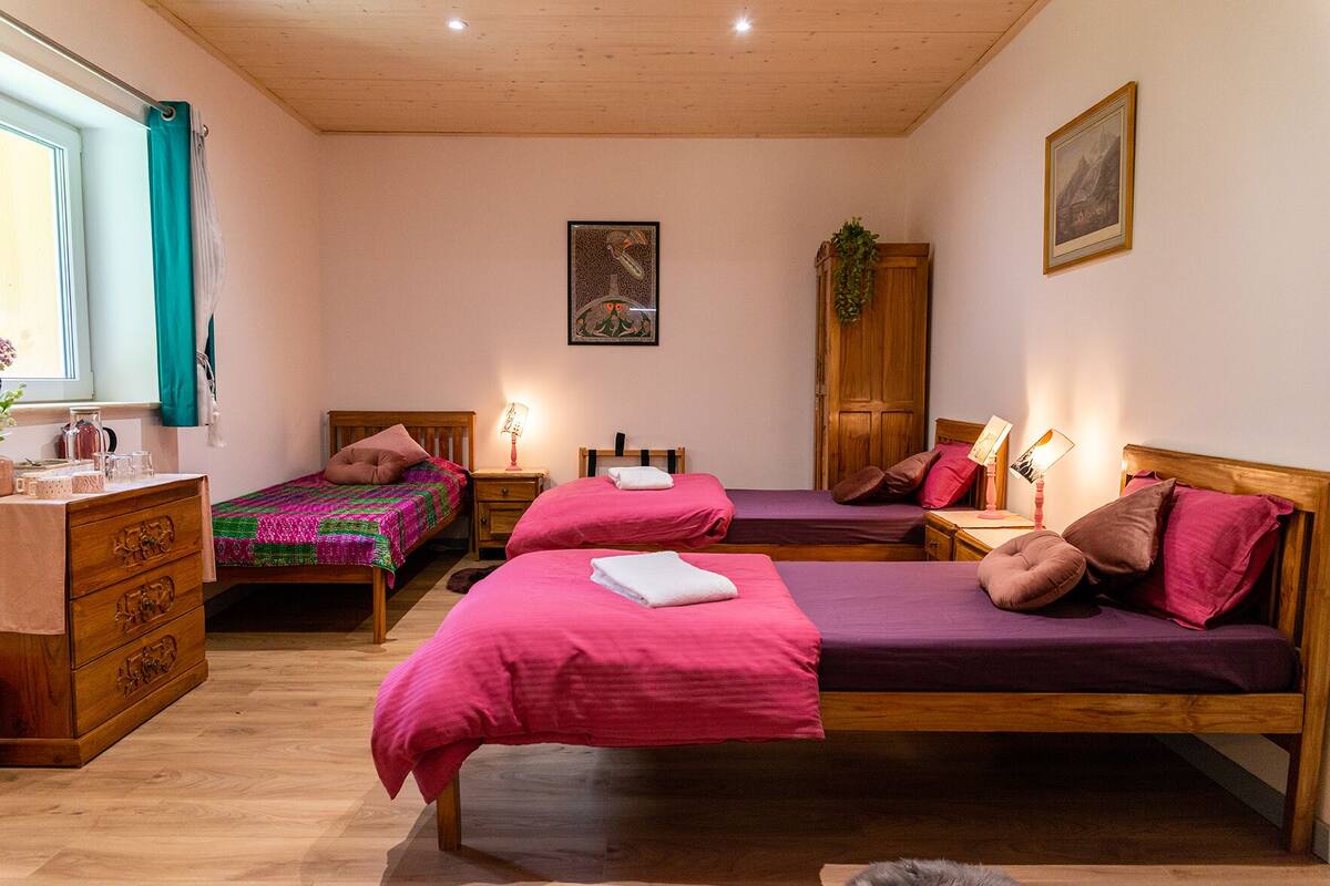 Een slaapkamer met twee bedden, houten meubels en een raam met gordijnen.