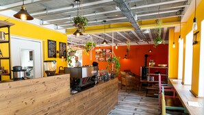 A restaurant interior with a wooden counter, hanging plants, and a red wall. - Chambres d'Hôtes Sanskriti (Scionzier)