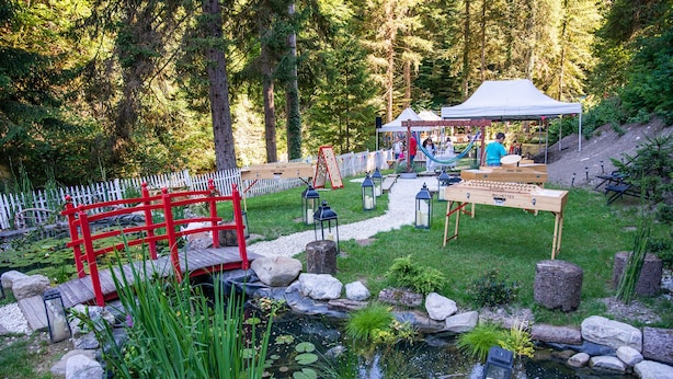 A garden with a pond, a red bridge, and a wooden table with a sign. - Chambres d'Hôtes Sanskriti (Scionzier)