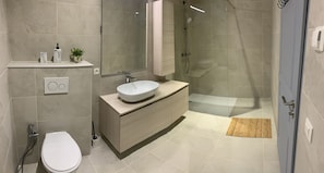 Een moderne badkamer met toilet, wastafel en douche.