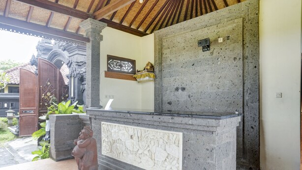 A stone altar with a relief sculpture, a wooden door, and a small shelf with a framed picture. - Hotel O Astiti Graha Tanah Lot (Tabanan)