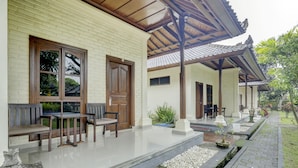 A traditional building with a tiled roof, wooden benches, and a stone pathway. - Hotel O Astiti Graha Tanah Lot (Tabanan)