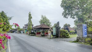 A street with a traditional building, a signboard, and a parking area. - Hotel O Astiti Graha Tanah Lot (Tabanan)
