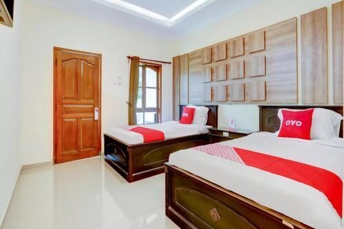 Una habitación de hotel con dos camas, una puerta de madera y un ventanal grande.