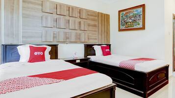Habitación de hotel con dos camas, cada una con colcha y almohadas rojas y blancas, cabecero de madera y una obra de arte colgada en la pared.
