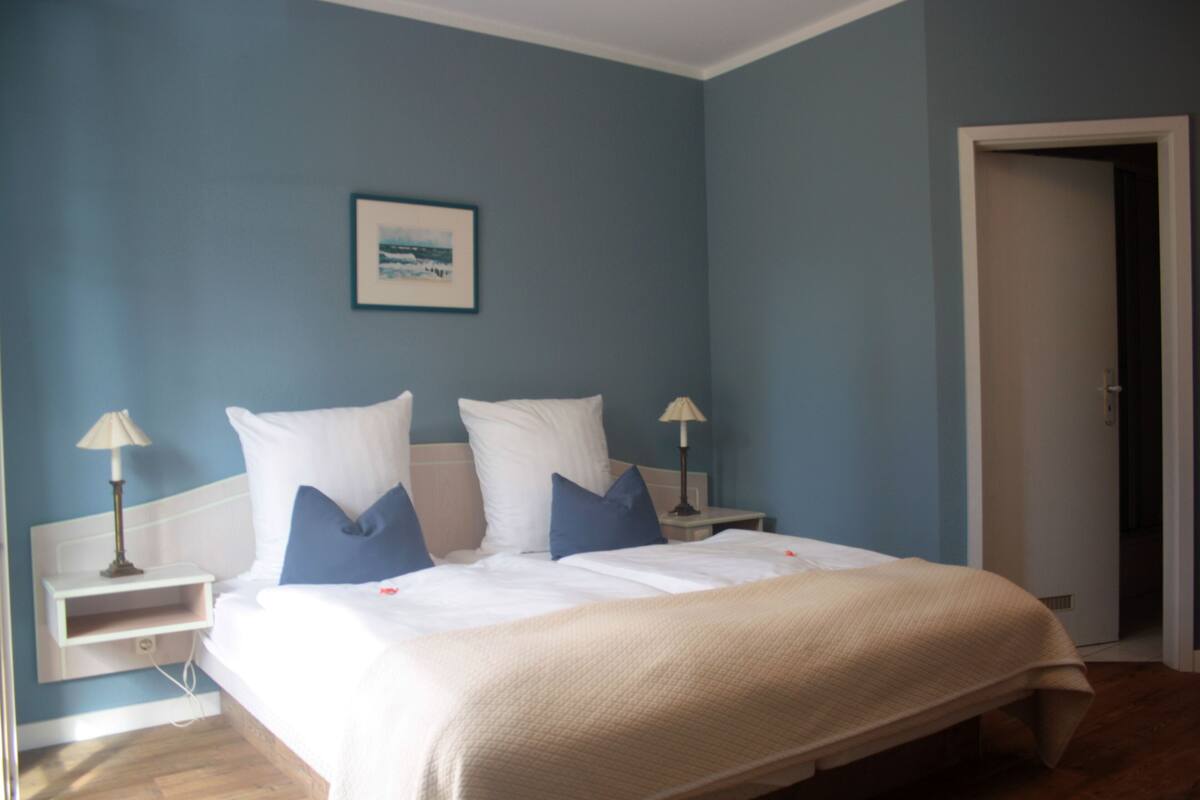 A bedroom with a bed, two bedside tables, and a nightstand.