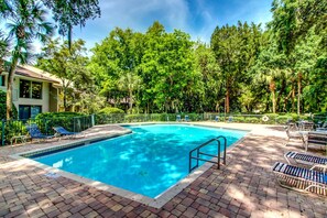Une piscine rectangulaire dont le bord est recouvert de carreaux, entourée d’une terrasse en briques.