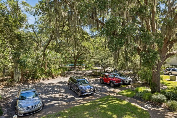 A parking area with multiple cars, surrounded by trees and greenery.