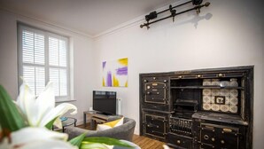 A living room with a television, a sofa, and a decorative cabinet with multiple compartments. - The Egerton at 52 Old Elvet (Durham)