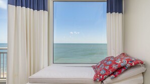 Ein Fensterplatz mit Meerblick, Vorhänge und ein Kissen.