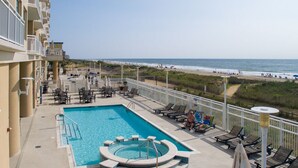 Ein Poolbereich mit Liegestühlen und Blick auf den Strand.