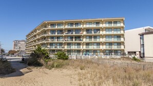 A multi-story hotel with balconies, located near a sandy beach area. - Two bedroom mid town with a pool and views! (Ocean City)
