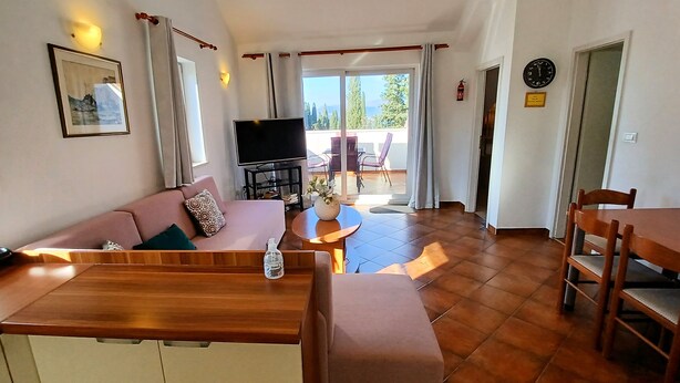Ein modernes Wohnzimmer mit Sofa, Fernseher und Essbereich mit Tisch und Stühlen.