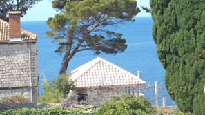 Un bâtiment situé sur la côte, doté d’un toit en tuiles, d’un mur en pierre et offrant une vue sur la mer.