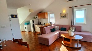 Ein Wohnzimmer mit einer Couch, einem Couchtisch, einem Fernseher und einer Küche im Hintergrund.