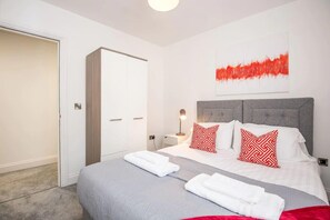 A modern bedroom with a grey bedspread, white pillows, and a red abstract painting on the wall. - The Gray at 52 Old Elvet (Durham)