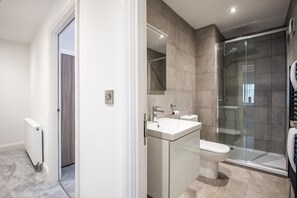 A modern bathroom with a glass shower enclosure, a white sink, and a toilet. - The Gray at 52 Old Elvet (Durham)