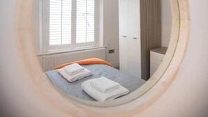 Een slaapkamer met een bed, een raam, een kledingkast en een radiator.