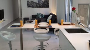 A modern kitchen with a dining area, white bar stools, and a large window with a mountain view. - ecoSmart Apartments Superior (Granada)