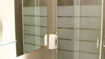 A bathroom with a glass shower enclosure, a white sink, and a mirror above the sink.