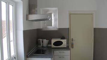 Una cocina pequeña con microondas, cafetera y lavabo.