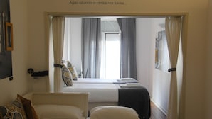 A hotel room with two beds, a window with curtains, and a view of the outside. - StayInn City - Évora (Évora)