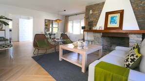 Un saló amb una xemeneia, una zona de menjador i una cuina al fons.