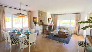 Zona d'estar àmplia amb taula de menjador, cadires, sofà i llar de foc.