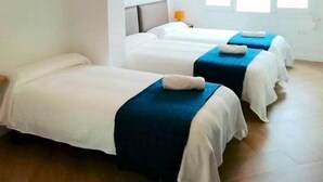 Habitació d'hotel amb dos llits, una finestra gran i un llum penjant.