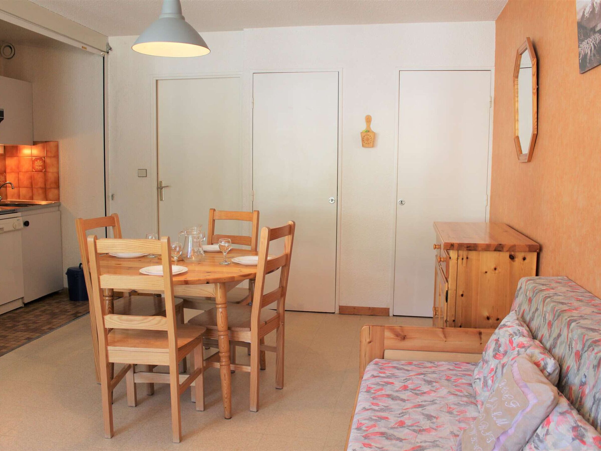 Espaço compacto para viver, com área de refeições, cozinha compacta e sofá.