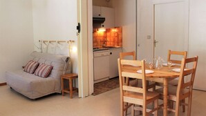 Un espace de vie compact comprenant un canapé, une table à manger avec des chaises et un coin cuisine.