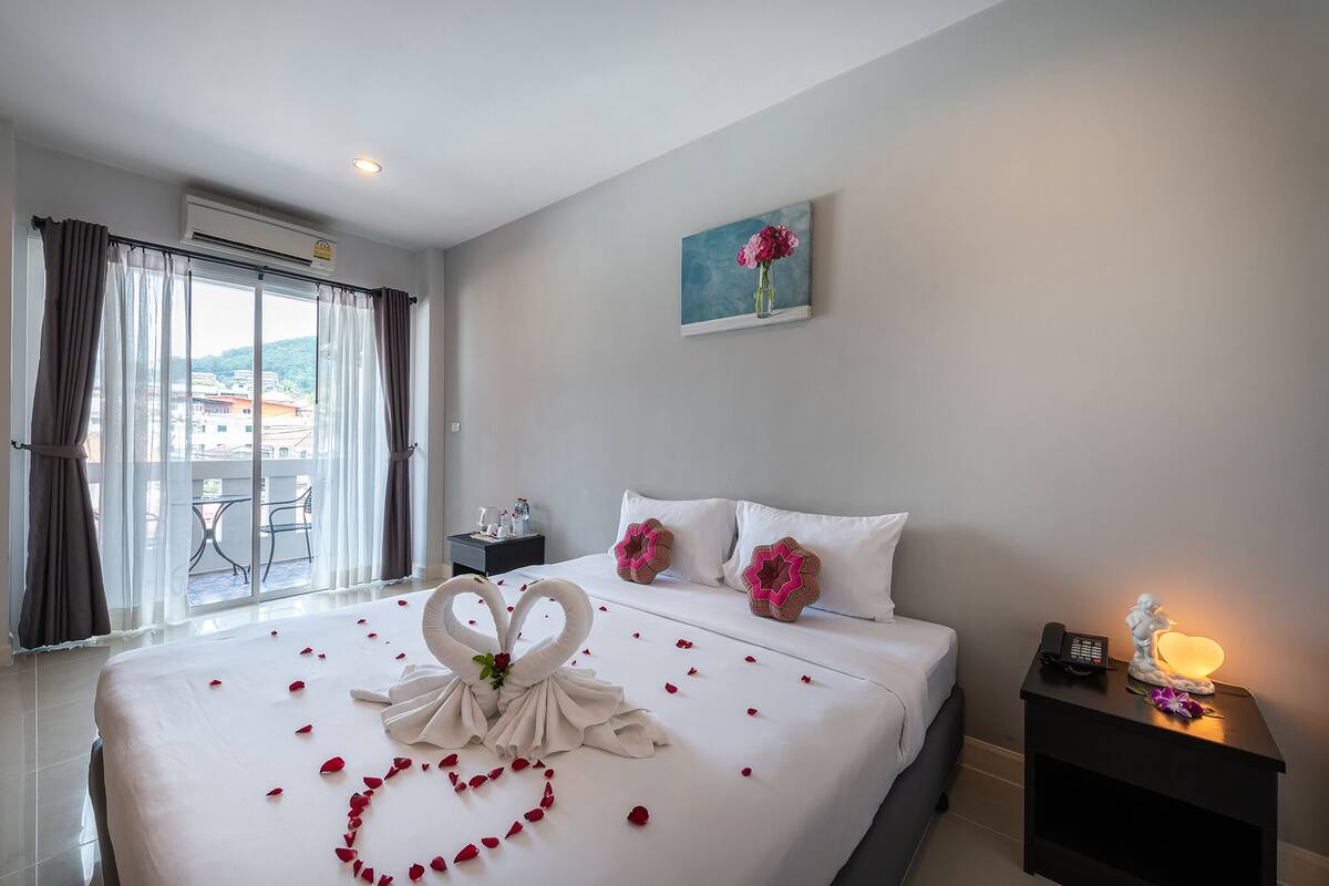 Une chambre d’hôtel avec un lit, une table de chevet, un tableau et une vue sur l’extérieur.
