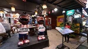 Ravintolan sisustus: puupöytiä, riippuvalaisimia ja kyltti, jossa lukee ”SUBPAROD RESTAURANT”.
