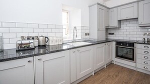 A modern kitchen with white cabinets, a black countertop, and a built-in oven. - The Kirkham at 52 Old Elvet (Durham)