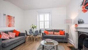 A modern living room with two grey sofas, a glass coffee table, a dining table with chairs, and a fireplace. - The Kirkham at 52 Old Elvet (Durham)