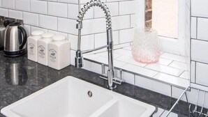 A modern kitchen with a white sink, stainless steel kettle, and tea bottles. - The Kirkham at 52 Old Elvet (Durham)