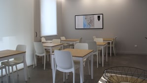 A classroom with white desks and chairs, a projector screen, and a map on the wall. - StayInn City - Póvoa de Varzim (Povoa De Varzim)