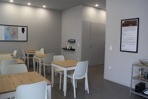 Une salle de conférence avec des tables et des chaises blanches, une carte accrochée au mur et une porte au fond.