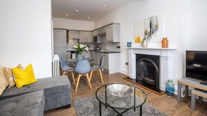 A modern living room with a grey sofa, a glass coffee table, and a fireplace. - The Langley at 52 Old Elvet (Durham)