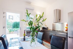 A modern kitchen with a dining table, chairs, and a vase of flowers. - GuestHost - The secret corner of Ferrara (Ferrara)