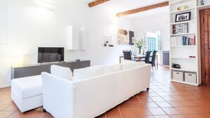A modern living room with a white sofa, a TV, and a bookshelf.