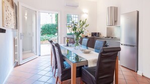 A modern kitchen with a glass dining table, stainless steel appliances, and a view to the outside.