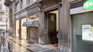 Vista de la calle con comercios cerrados, un aparcamiento para bicicletas y un edificio con un letrero que dice 'BPM'.
