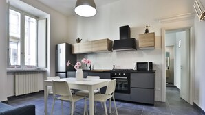 A modern kitchen with a dining table, chairs, a refrigerator, stove, and a microwave. - GuestHost - Garibaldi huge and cozy apartment (Napoli)