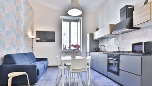 A modern kitchen with a dining area, a sofa, and a TV. - GuestHost - Garibaldi huge and cozy apartment (Napoli)