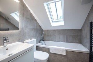 A modern bathroom with a skylight, a bathtub, and a toilet. - The Talbot at 52 Old Elvet (Durham)
