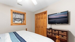 A bedroom with a bed, a television, a wardrobe, and a framed picture on the wall.