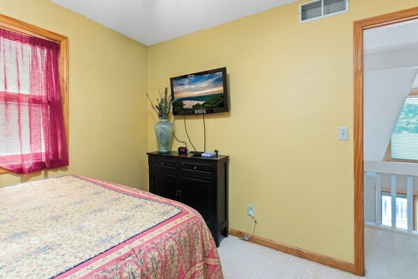 A bedroom with a bed, a dresser, a TV, and a window with curtains. - Casa Del Sol - Three Bedroom House, Sleeps 10 (Rocky Mount)