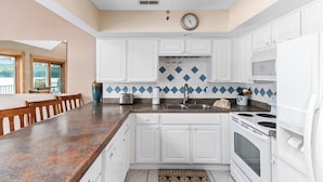 A kitchen with white cabinets, a granite countertop, a stove, and a sink.