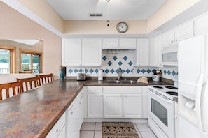 A kitchen with white cabinets, a granite countertop, a stove, and a sink. - Casa Del Sol - Three Bedroom House, Sleeps 10 (Rocky Mount)